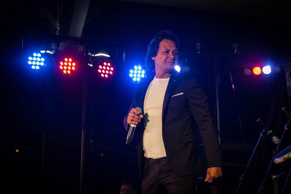 A man in a suit is singing into a microphone on a stage.