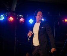 A man in a suit is standing on a stage holding a microphone.