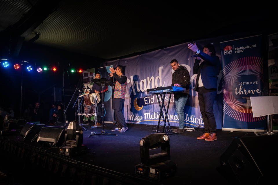 A group of people are standing on a stage with their hands in the air.