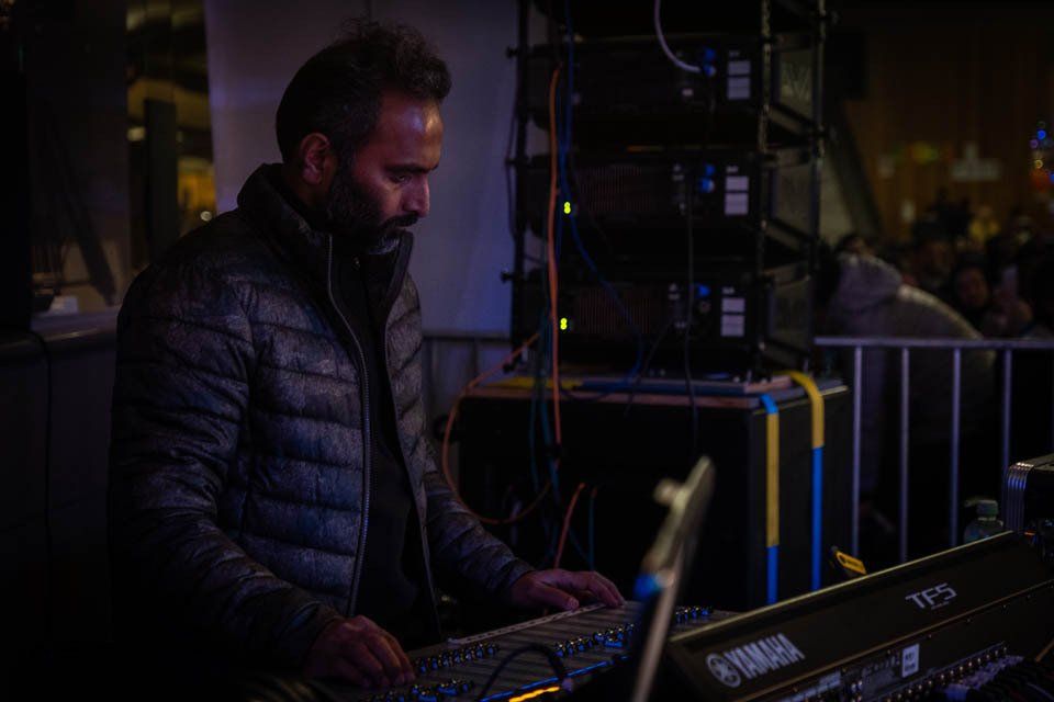A man is playing a keyboard in a dark room.