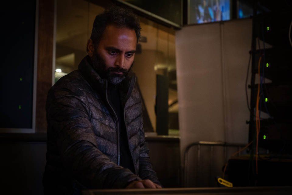 A man with a beard is standing in a dark room.