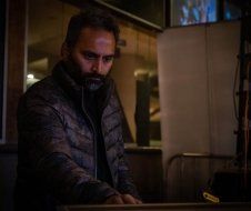 A man with a beard is standing in a dark room.