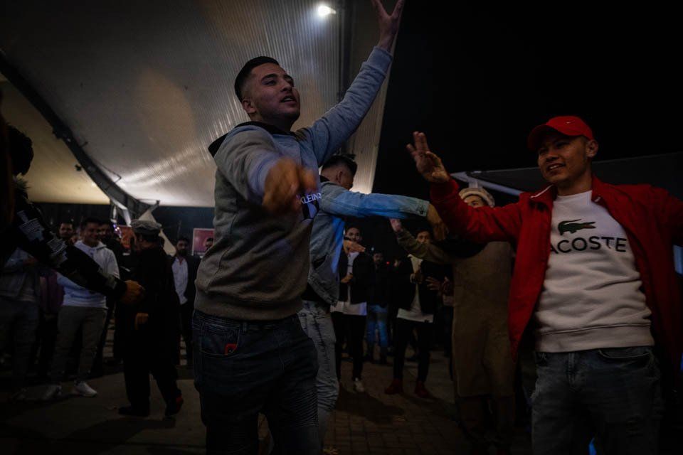 A group of men are dancing in a dark room.