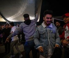 A man in a denim jacket is standing in a crowd of people.