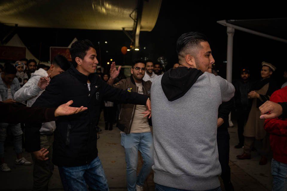 A group of young men are dancing together in a dark room.