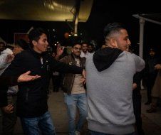 A group of young men are dancing together in a dark room.