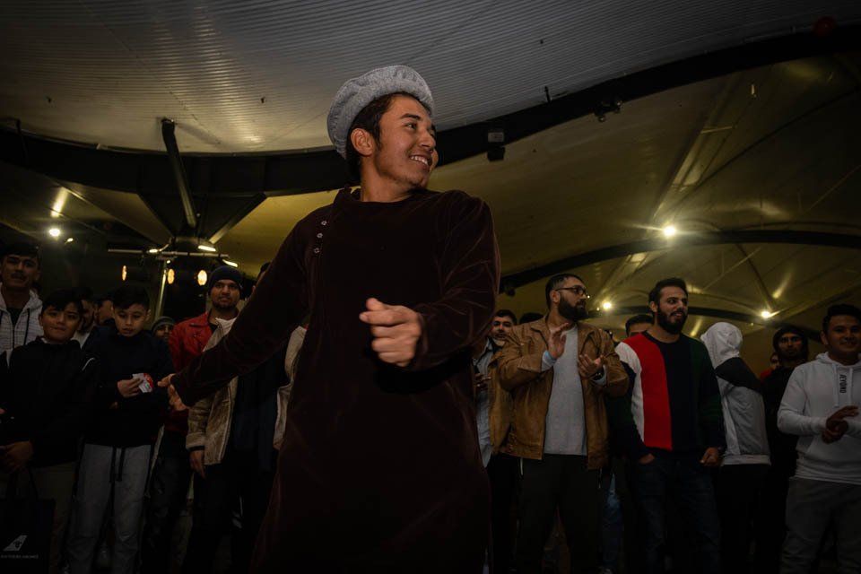 A man in a hat is dancing in front of a crowd of people.