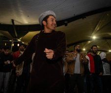 A man is dancing in front of a crowd of people in a dark room.