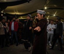 A group of men are dancing in a dark room.