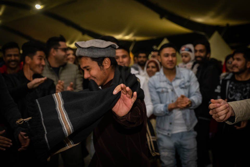A man in a hat is dancing in front of a crowd of people.