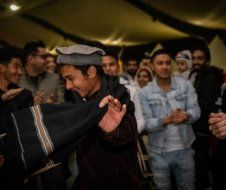 A man in a hat is standing in front of a crowd of people.