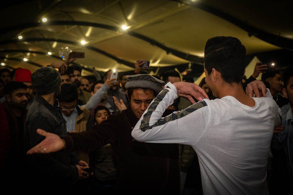 A man in a white shirt is dancing in front of a crowd of people.