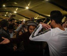 A man in a white shirt is dancing in front of a crowd of people.