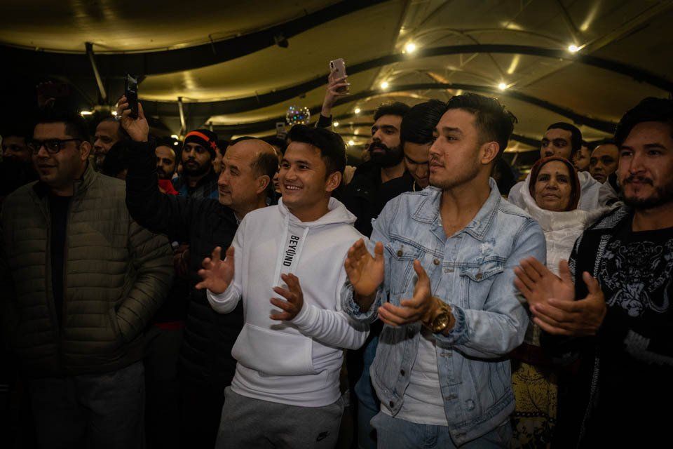 A group of people are standing in a room clapping their hands.