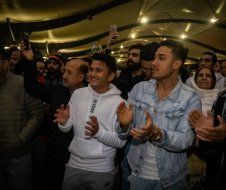 A group of people are standing in a room clapping their hands.