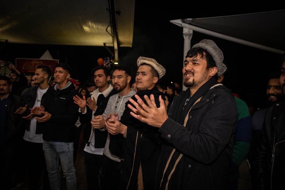 A group of men are clapping their hands in a dark room.