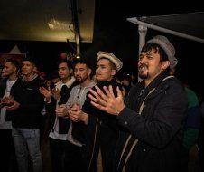 A group of men are clapping their hands in a dark room.
