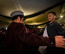 A man in a hat is dancing with another man in a room.