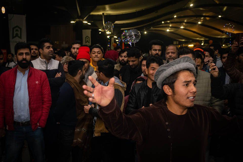A man in a hat is standing in front of a crowd of people.