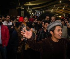 A man in a hat is standing in front of a crowd of people.