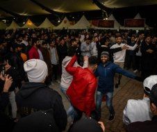 A large group of people are dancing in a tent.