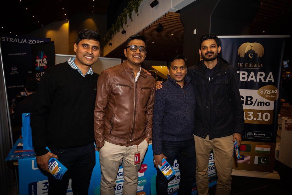 A group of men are posing for a picture in front of a sign.