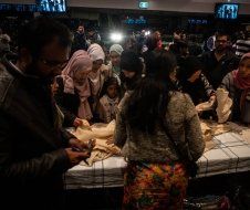 A group of people are standing around a table with a body on it.
