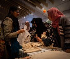 A group of women are standing around a table looking at clothes.