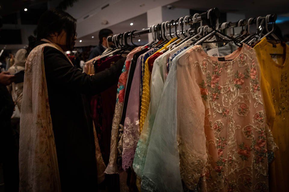 A woman is looking at clothes hanging on a rack in a store.