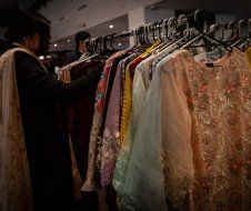 A woman is looking at clothes on a rack in a store.