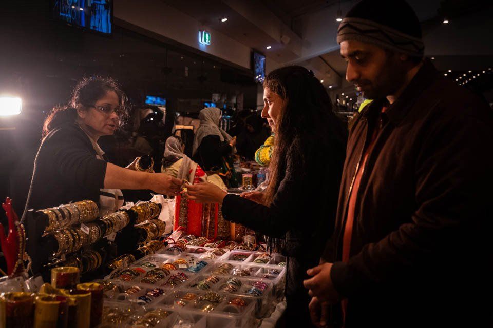 A woman is selling bracelets to a man at a market.