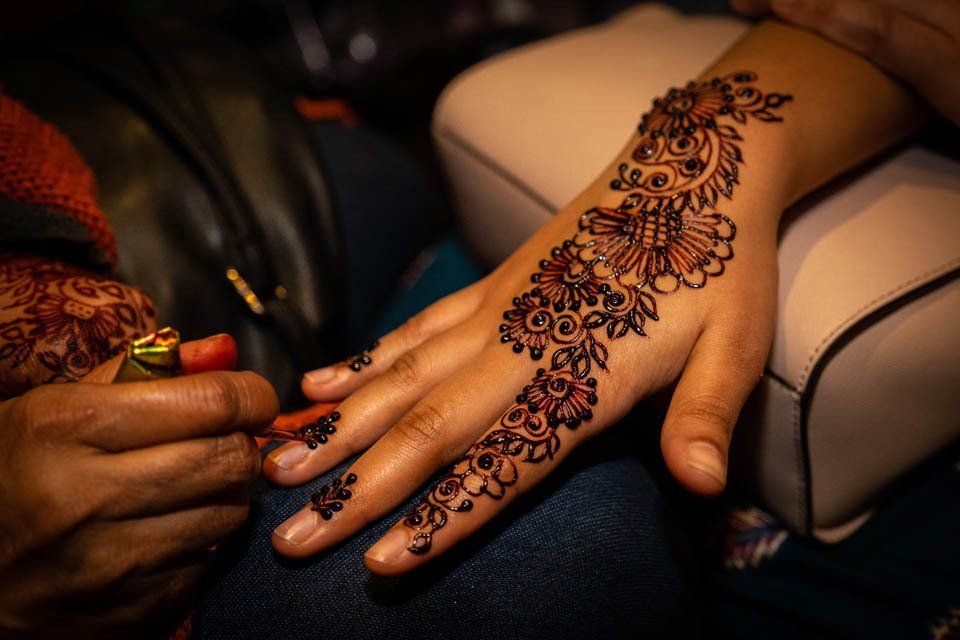 A woman is getting a henna tattoo on her hand.