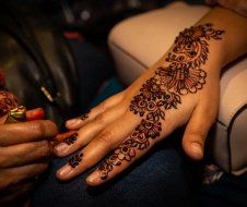 A woman is getting a henna tattoo on her hand.