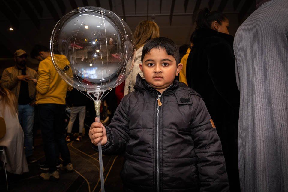 A young boy is holding a clear balloon in his hand.