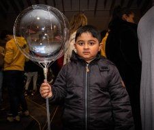 A young boy is holding a clear balloon in his hand.