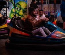 A man is riding a bumper car at an amusement park.
