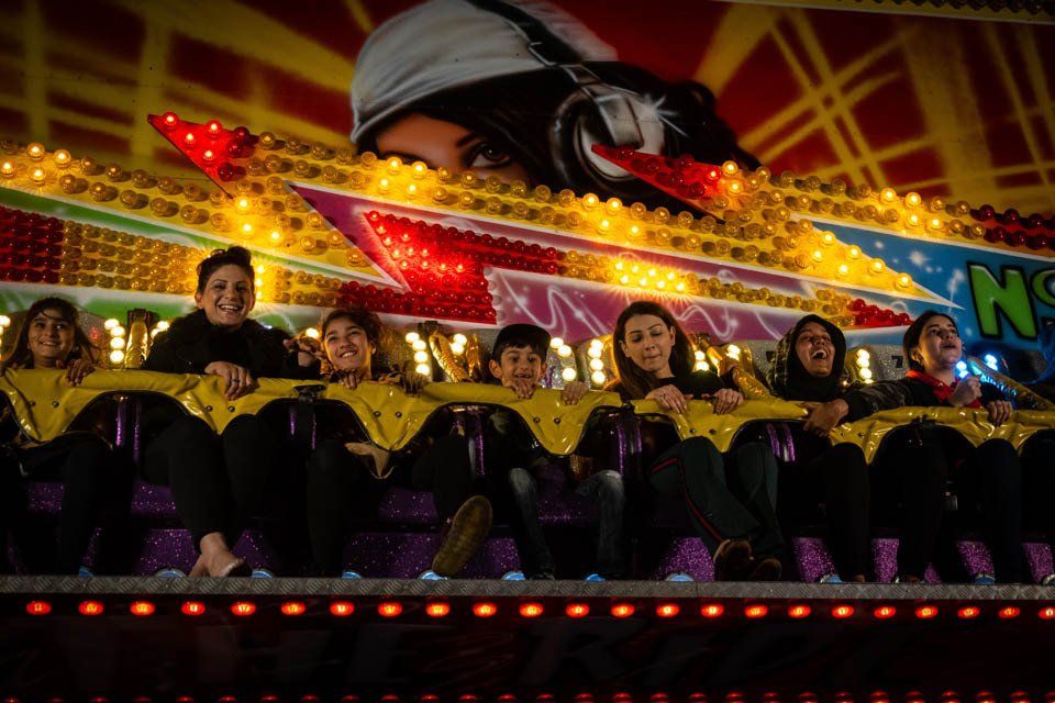A group of people are riding a roller coaster at an amusement park.