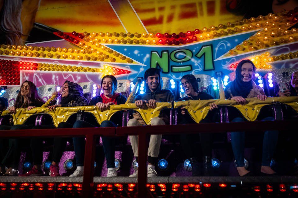 A group of people are riding a roller coaster at a carnival.