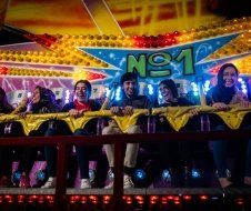 A group of people are riding a roller coaster at a carnival.