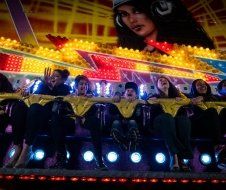 A group of people are riding a roller coaster at a carnival.