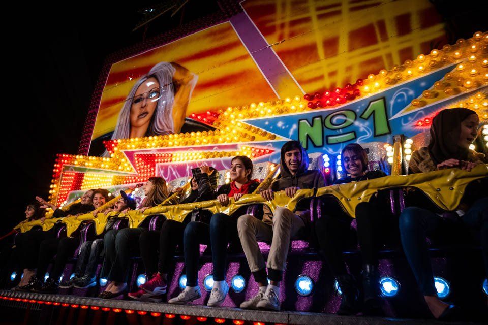 A group of people are riding a roller coaster at a carnival.
