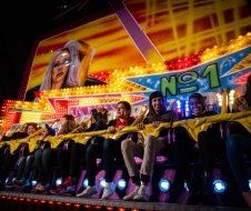 A group of people are riding a roller coaster at night.