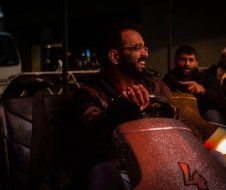 A man with a beard is driving a bumper car at night.
