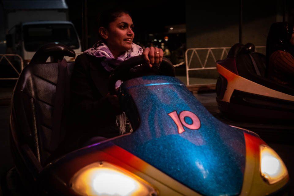 A woman is riding a bumper car at a carnival at night.