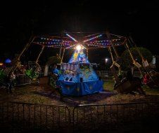 A group of people are riding a merry go round at a carnival at night.
