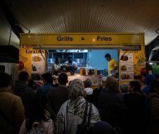 A crowd of people are standing in line at a food truck.