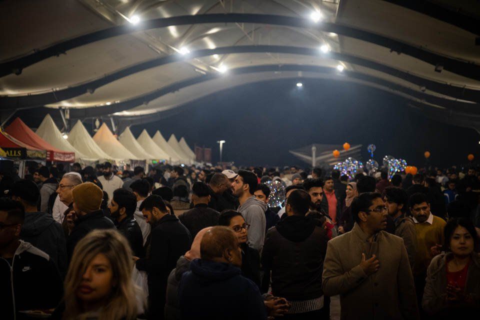 A crowd of people are gathered under a tent at a festival.