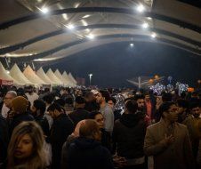 A crowd of people are gathered under a tent at night.