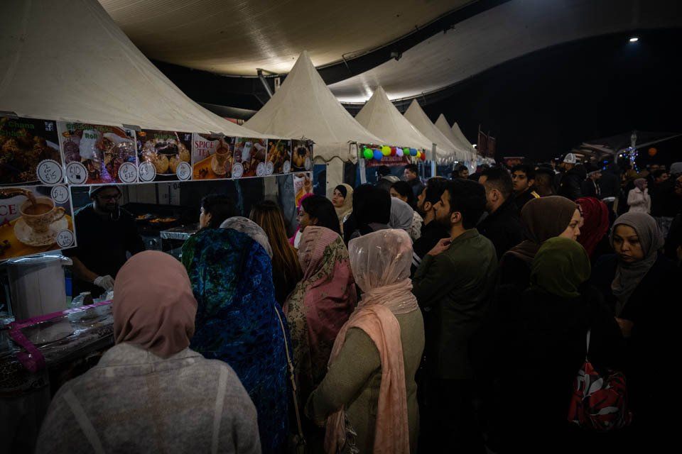 A large group of people are standing in a line at a food festival.
