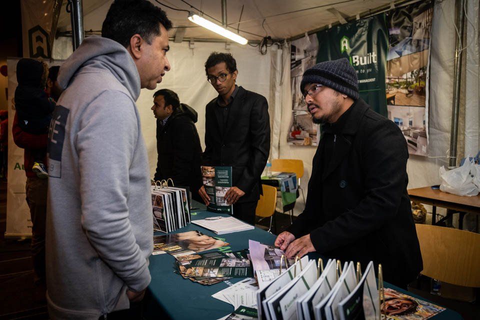 A group of men are standing around a table talking to each other.